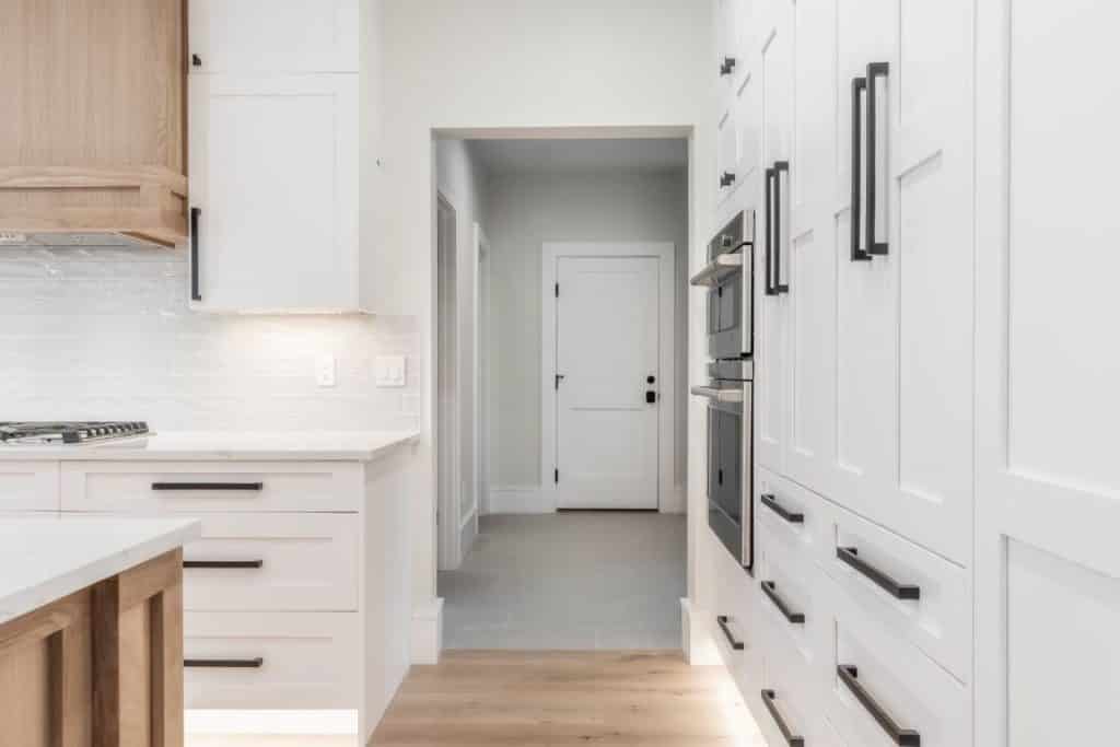 modern kitchen with white shaker cabinets and maple wood floors