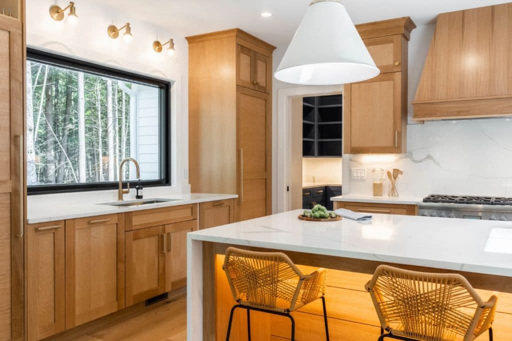 Frameless white oak cabinets wrap around the perimeter of this recently redesigned kitchen. A large island with a white quartz countertop sits in its center.