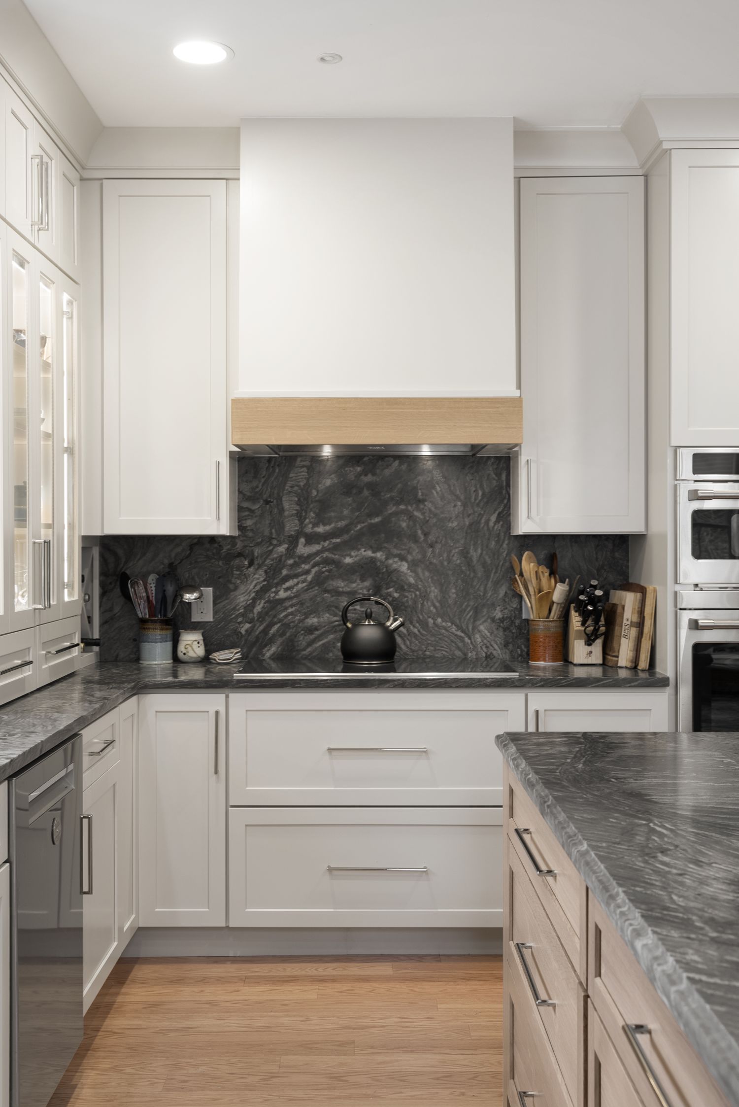 White shaker kitchen with a dark granite slab backsplash and countertops in a Maine home