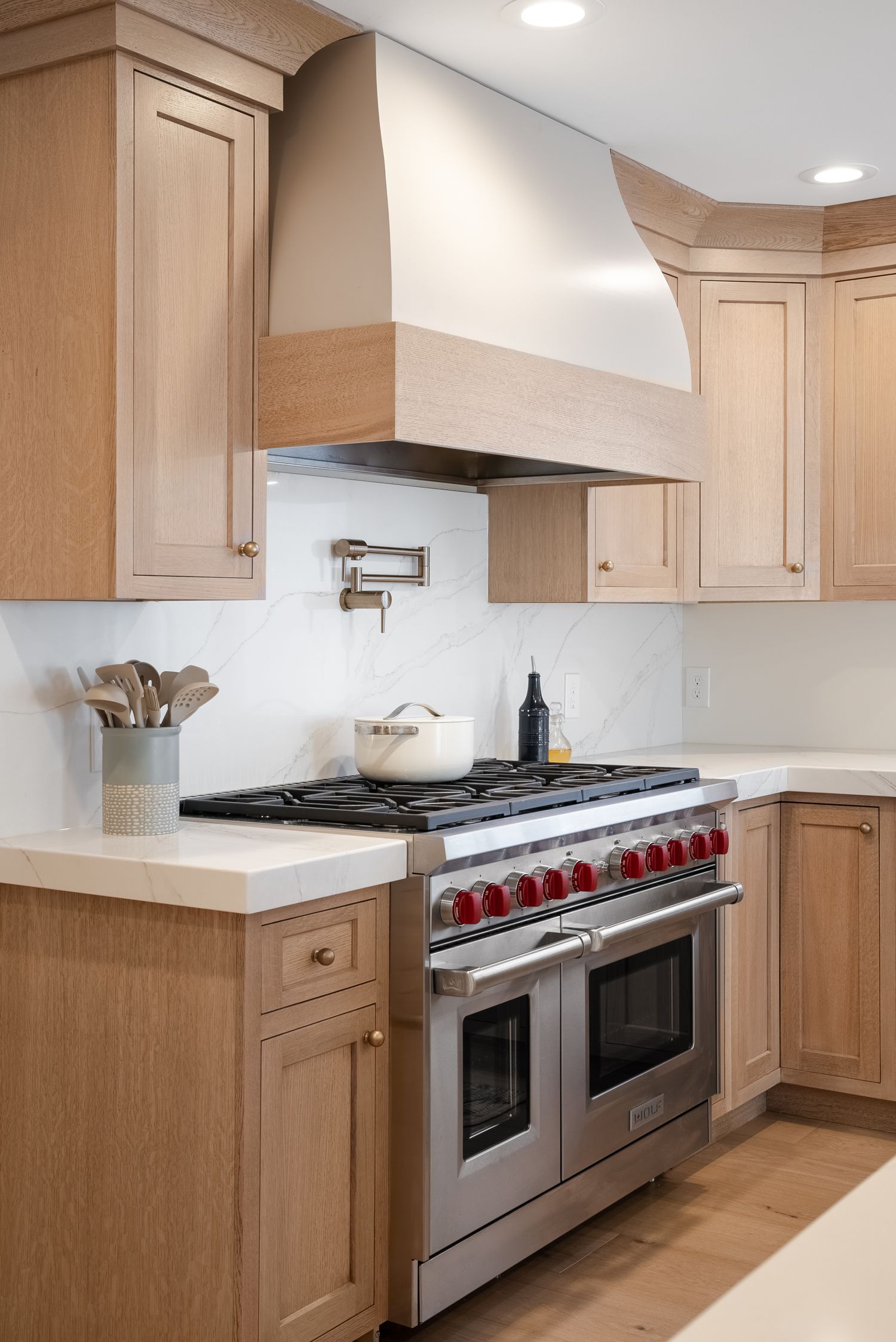 White oak kitchen with a white marble slab backsplash and countertops, built by Maine Cabinet Company