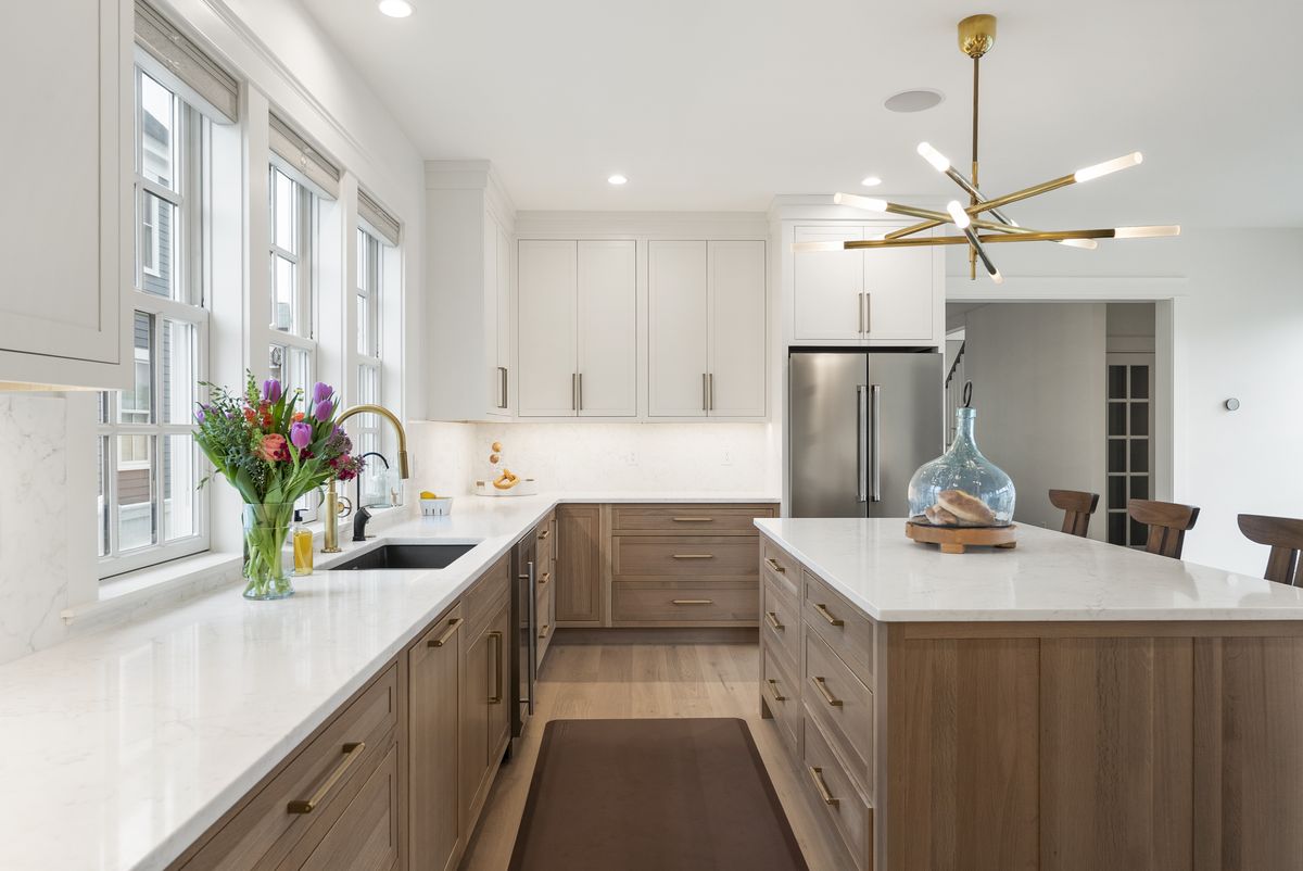 White oak perimeter cabinetry and quartz countertops beneath a window wall in a Scarborough, Maine kitchen