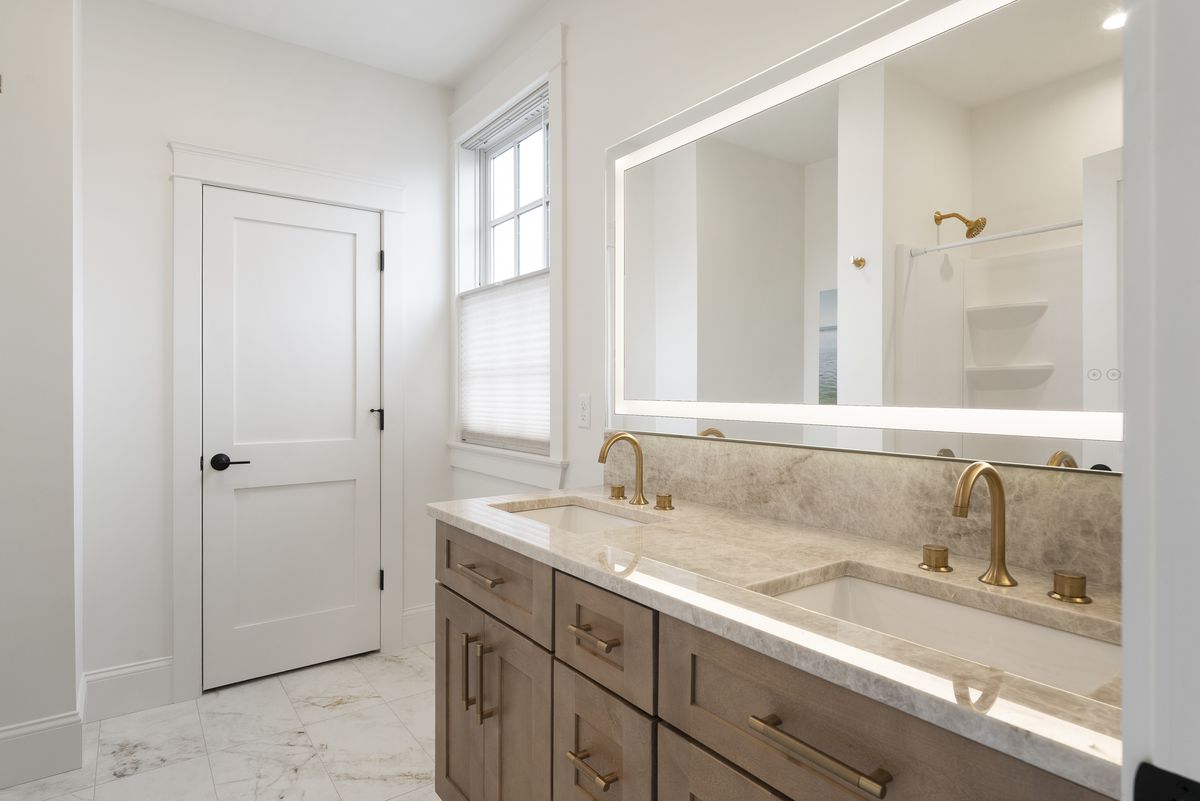 Custom white oak double vanity with brass fixtures in a Scarborough, Maine primary bathroom