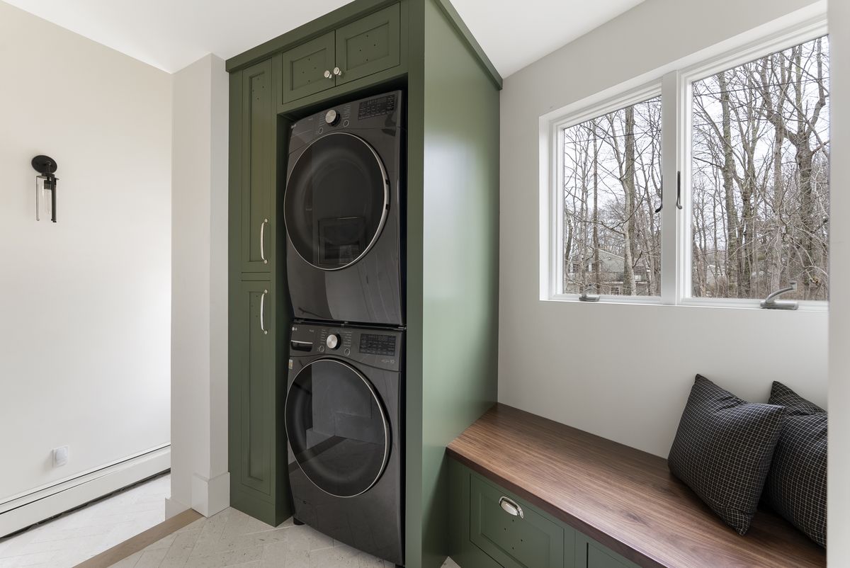Green painted laundry cabinetry with a walnut bench seat in a Yarmouth, Maine mudroom